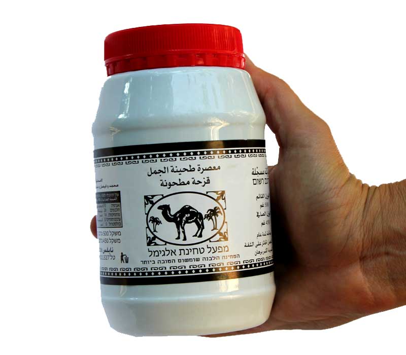 A jar of tahini sauce with a red cap on a white label, featuring text and a logo that suggests it is a product based on Nigella sativa.