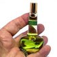Hand holding a small bottle with green liquid against a white background