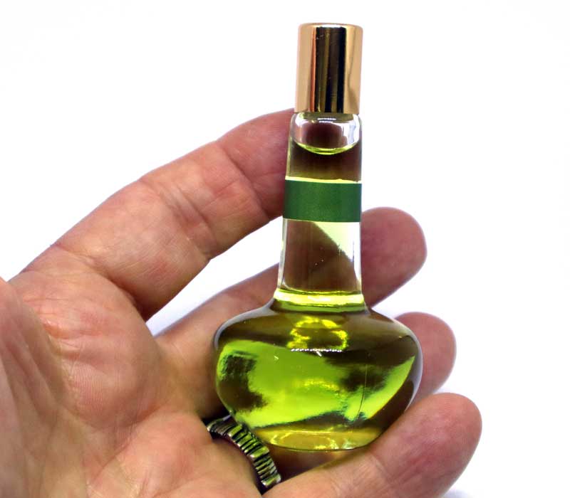 Hand holding a small bottle with green liquid against a white background