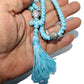Hand holding a blue beaded prayer rope with tassel against a white background