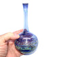 Hand holding a glass vase with a gradient color effect on a white background