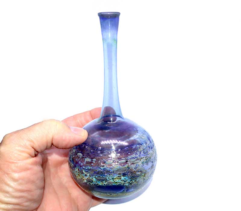 Hand holding a glass vase with a gradient color effect on a white background