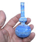 Hand holding a blue glass bottle with a white marbled pattern on a white background