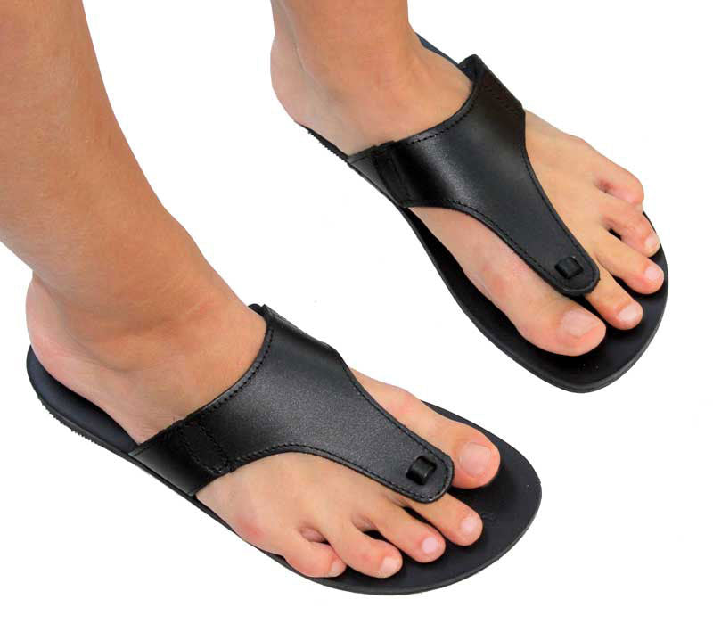 A pair of black leather sandals with straps, worn by a person standing against a white background.