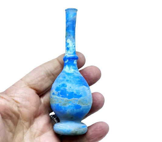 Blue glass pipe held in a hand against a white background